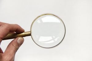 A hand holding a magnifying glass