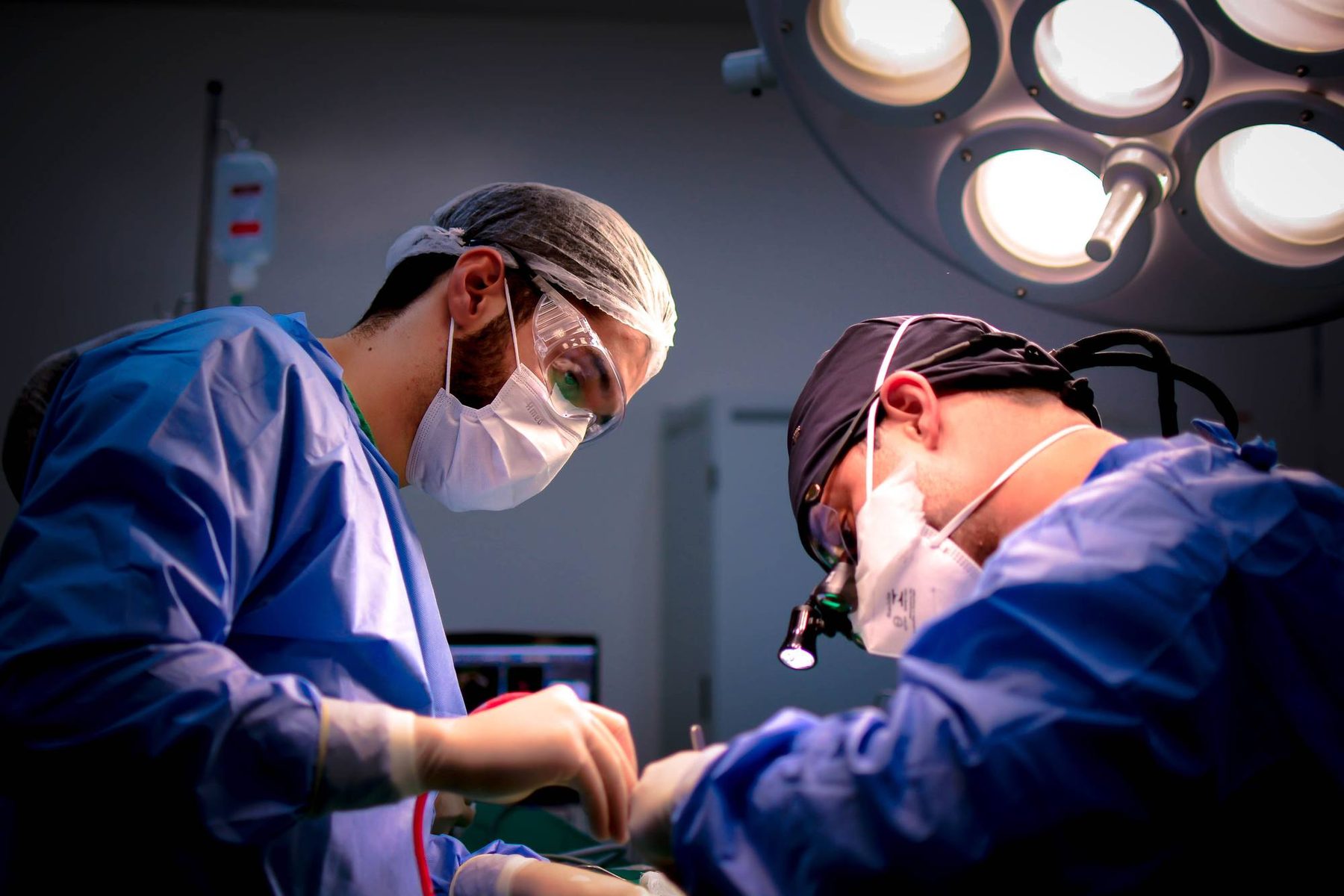 Two clinicians working under theatre lights during a procedure